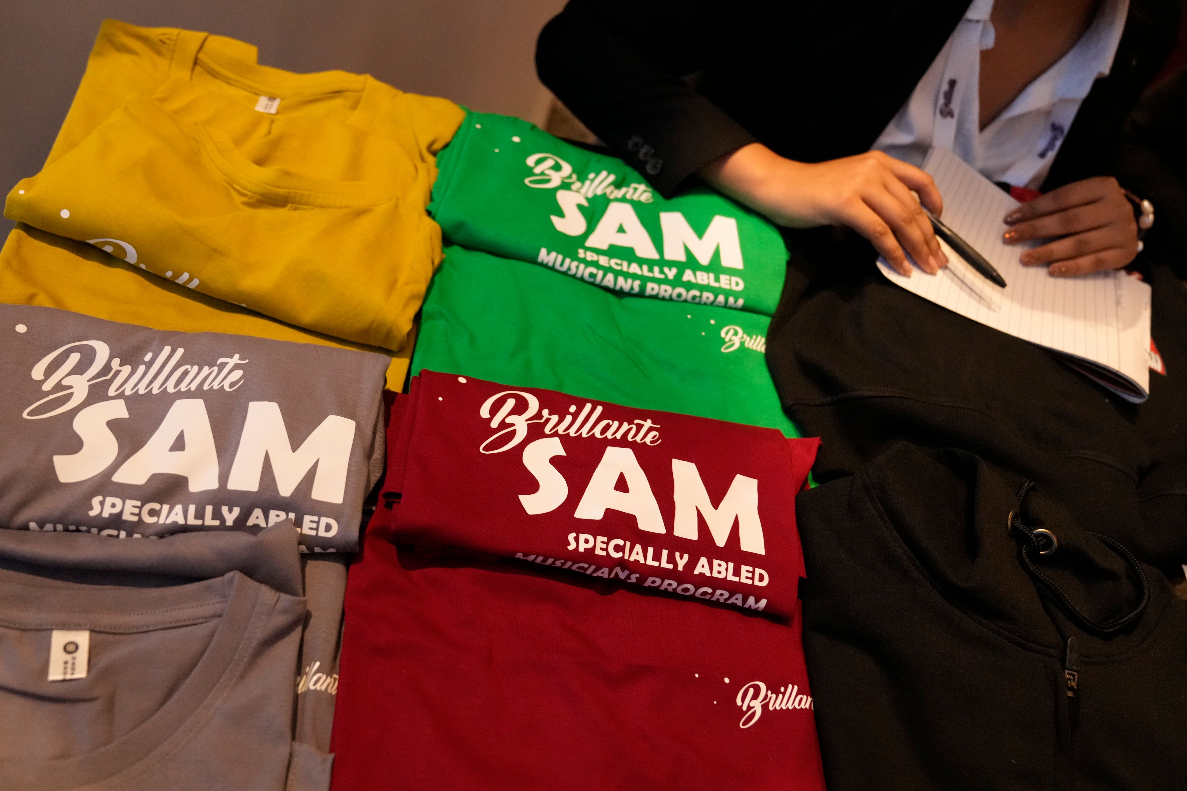 T-shirts featuring Specially Abled Musicians (SAM) program logos are displayed for sale outside an auditorium at the two-day Brillante Piano Festival in Bengaluru, India, Sunday, Sept. 29, 2024. (AP Photo/Aijaz Rahi)