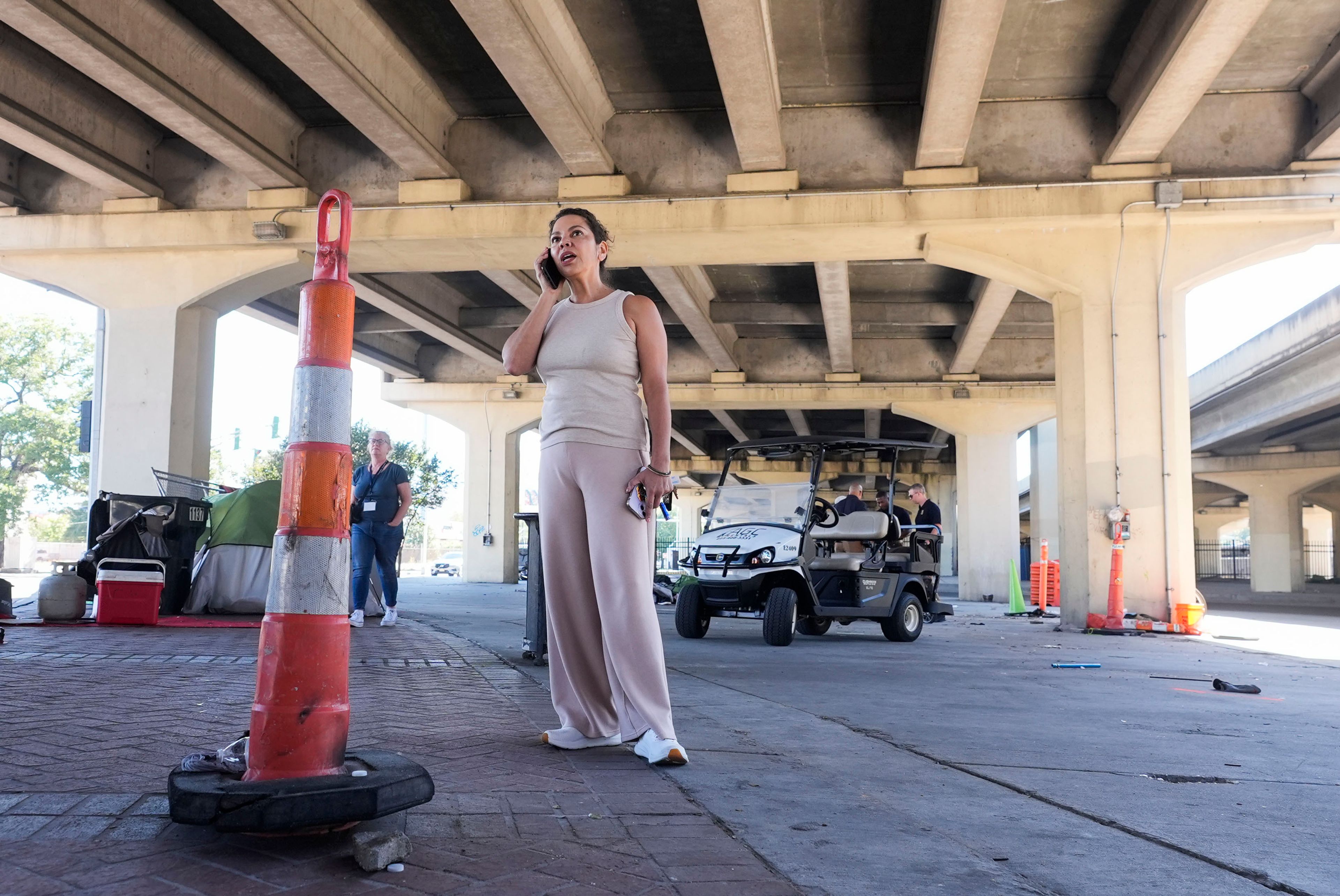 New Orleans City council member Lesli Harris talks on the phone as Louisiana State police give instructions to people living in a homeless encampment to move to a different pre-designated location as they perform a sweep in advance of a Taylor Swift concert in New Orleans, Wednesday, Oct. 23, 2024. (AP Photo/Gerald Herbert)