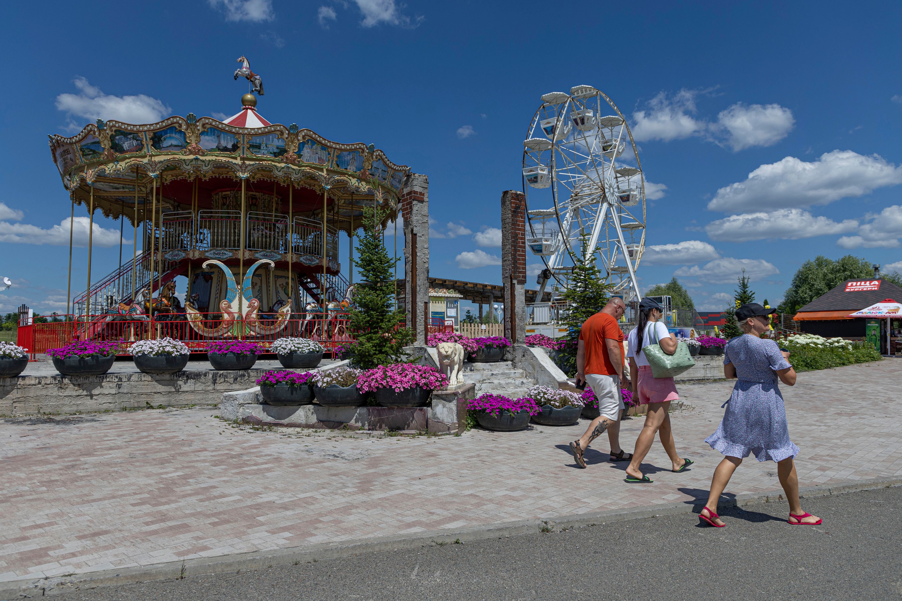 People walk by the flower-decorated remains of the entrance to Dobro Park hotel, which was burned and destroyed during the Russian occupation of Kyiv region, in Motyzhyn, Kyiv region, Ukraine, Wednesday, June 26, 2024. Dobro Park, a 370-acre (150 hectare) privately-run garden and recreation area west of Kyiv, was rebuilt after the Russian attack and occupation that lasted for more than a month. (AP Photo/Anton Shtuka)