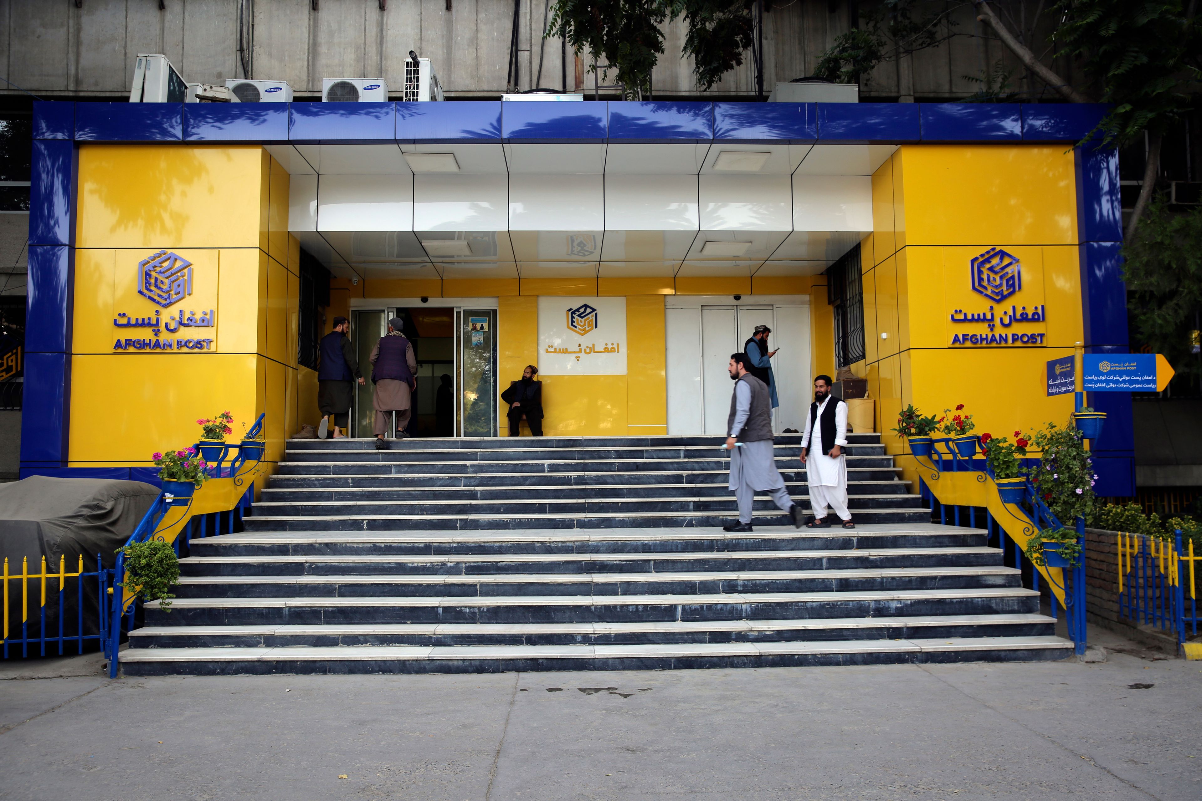 Afghans enter into the main post office to receive their post in the city of Kabul, Afghanistan, Wednesday, July 3, 2024. In parts of Afghanistan where there are no street names or house numbers, utility companies and their customers have adopted a creative approach for connecting. They use mosques as drop points for bills and cash, a "pay and pray" system. (AP Photo/Siddiqullah Alizai)