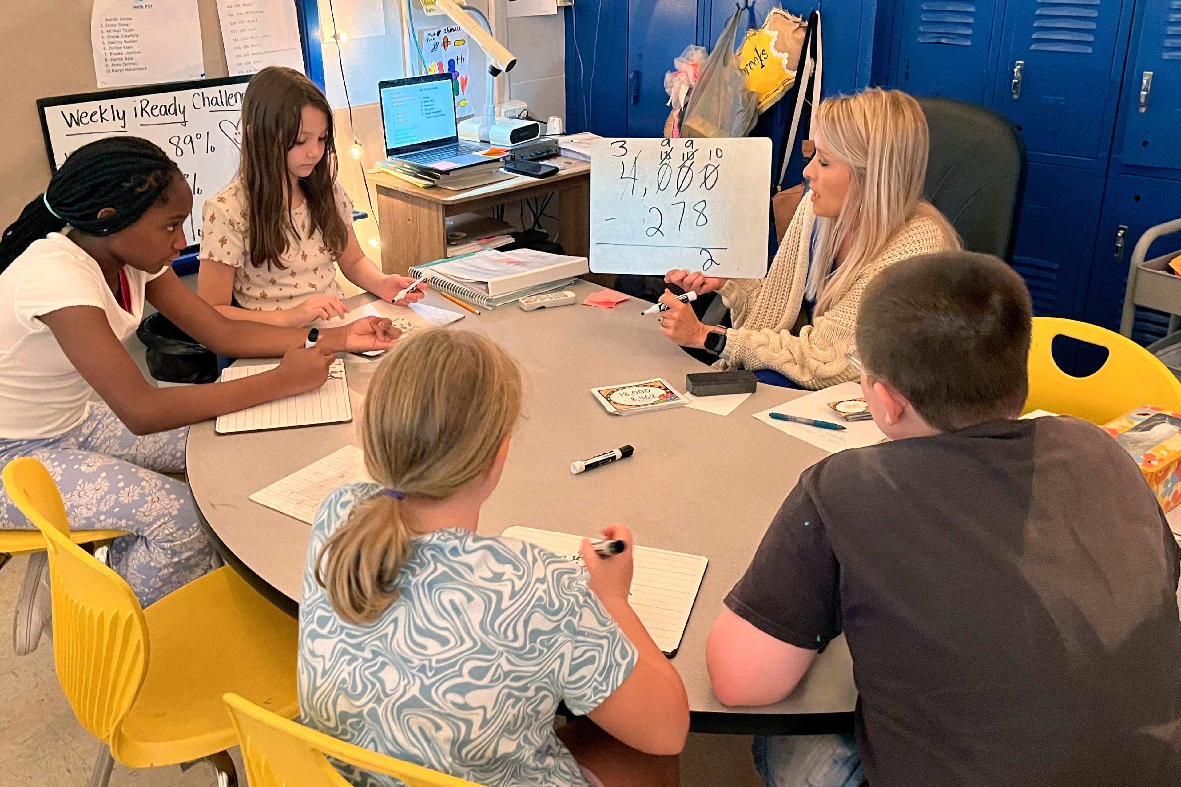 Piedmont Elementary School math teacher Cassie Holbrooks helps a small group of fourth-grade students with a three-digit subtraction problem in Piedmont, Ala., on Thursday, Aug. 31, 2023. Piedmont, a 1,100-student district where seven out of 10 qualify for free or reduced-prince lunch, has stuck with an approach it began before the pandemic: It gave teachers more time to dig into data on student performance and increased instructional time for math teachers to focus on specific skills. (Trisha Powell Crain/AL.com via AP)