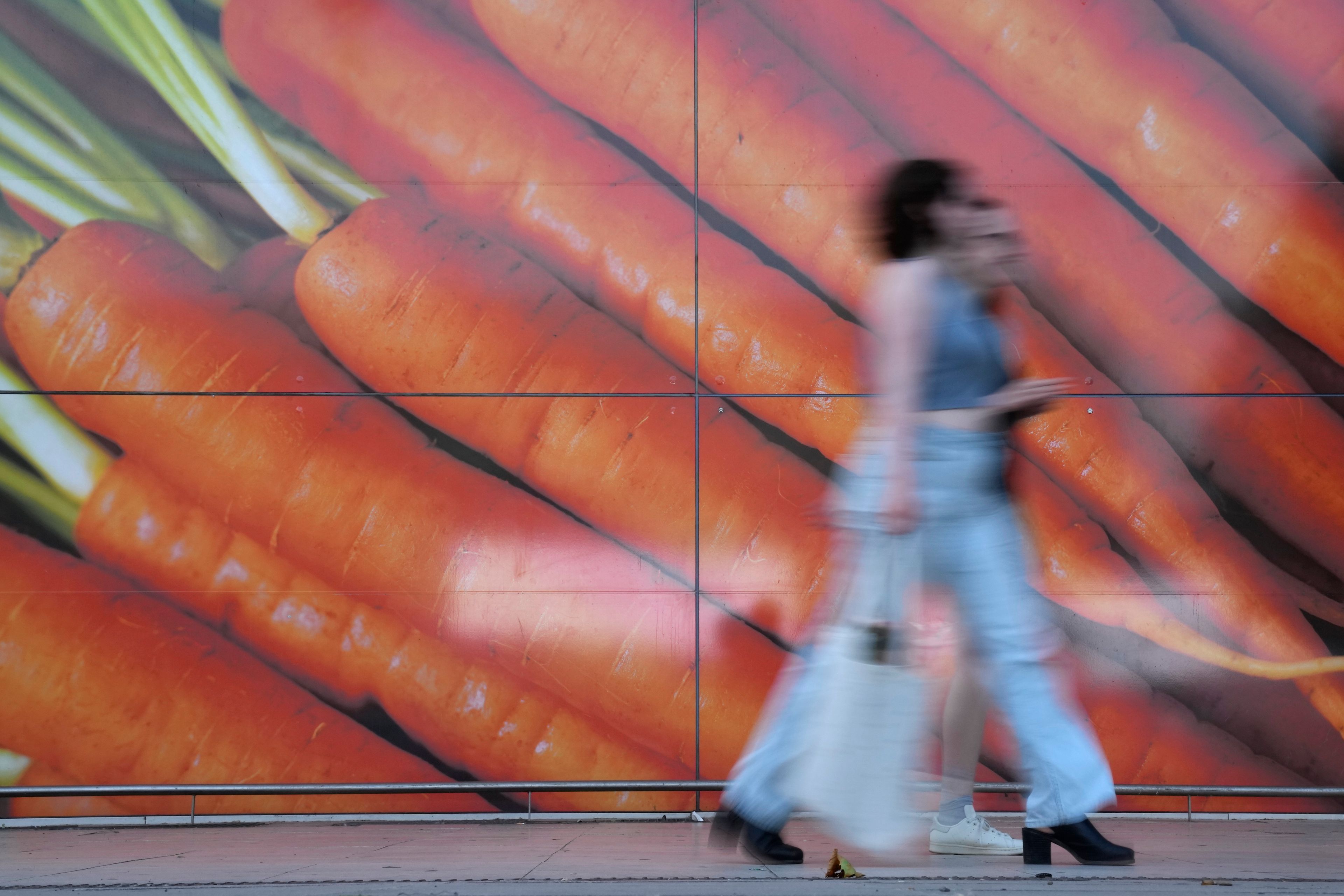 Shoppers walk past a large poster outside a supermarket in London, Saturday, June 10, 2023. High food prices are pinching households across Europe, where food inflation is outpacing other major economies like the U.S., Japan and Canada. Some governments have responded with formal price controls or loose agreements with supermarkets to keep costs down. (AP Photo/Alastair Grant)