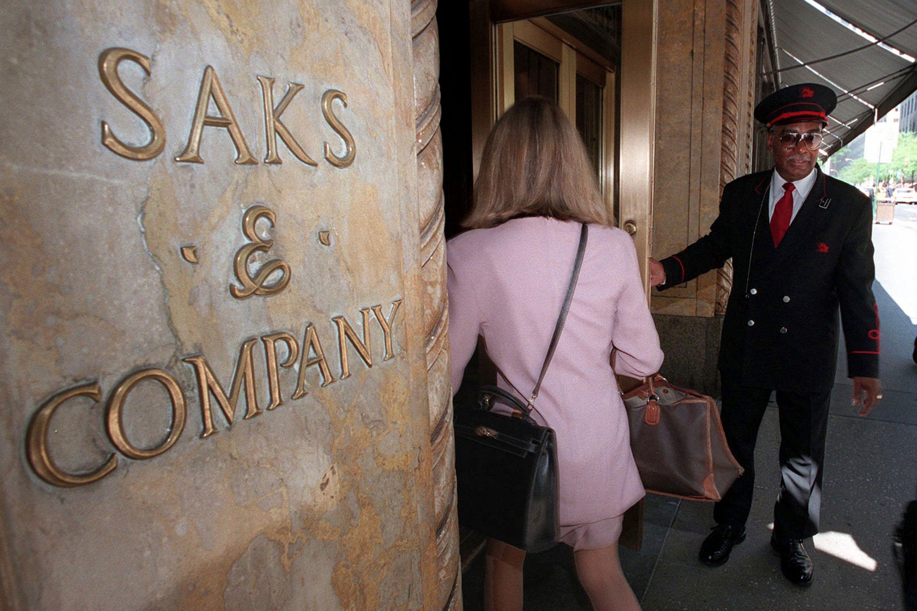 FILE — A Saks & Company doorman opens the 50th Street store entrance for customers, in New York, May 21, 1996. The parent company of Saks Fifth Avenue has signed a deal to buy upscale rival Neiman Marcus for $2.65 billion. The buyout was announced Thursday, July 4, 2024, after months of rumors that the department store chains had been negotiating a deal. (AP Photo/Richard Drew, File)