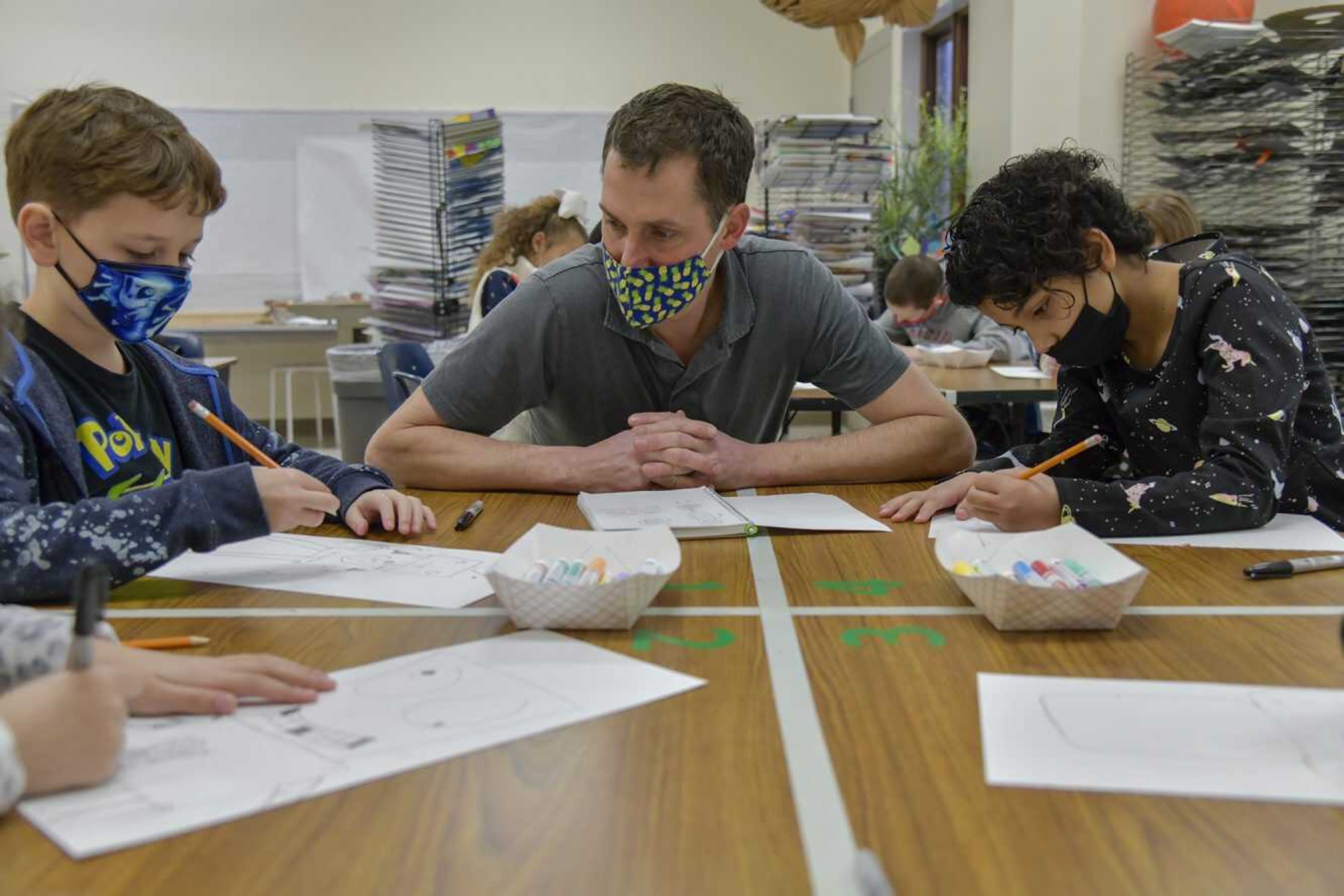 Center, art teacher Matthew Miller gives some advice on the bots of Levi Anderson, left, and Alivia Johnson, right, as they work on them at Blanchard Elementary in Cape Girardeau on Thursday, Jan. 28, 2021.