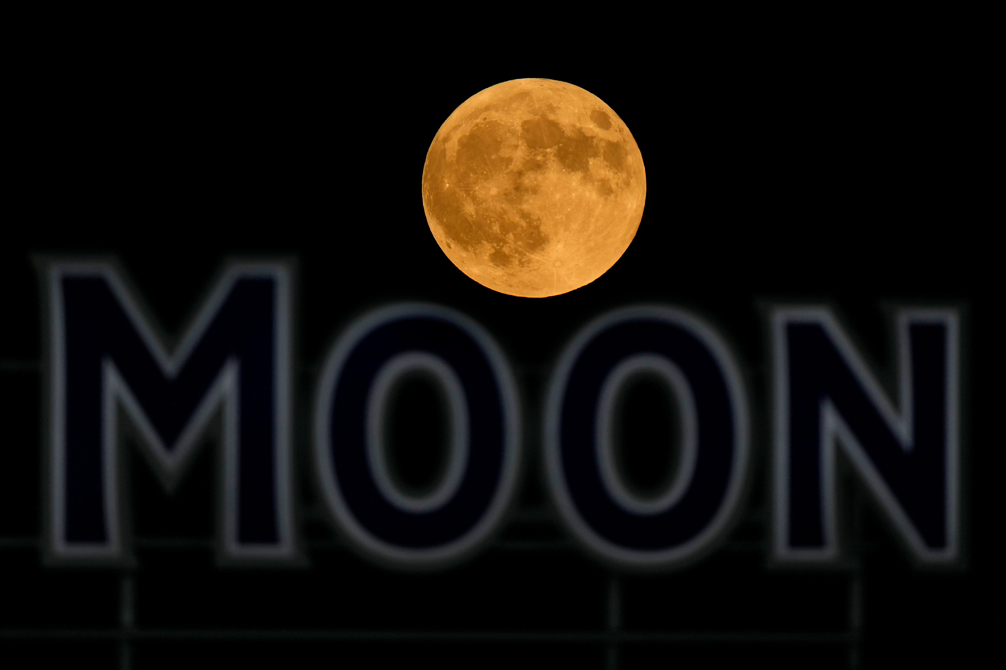 The full moon rises in the over a beer sign in the outfield at Kauffman Stadium during a baseball game between the Kansas City Royals and the Detroit Tigers, Tuesday, Sept. 17, 2024, in Kansas City, Mo. (AP Photo/Charlie Riedel)