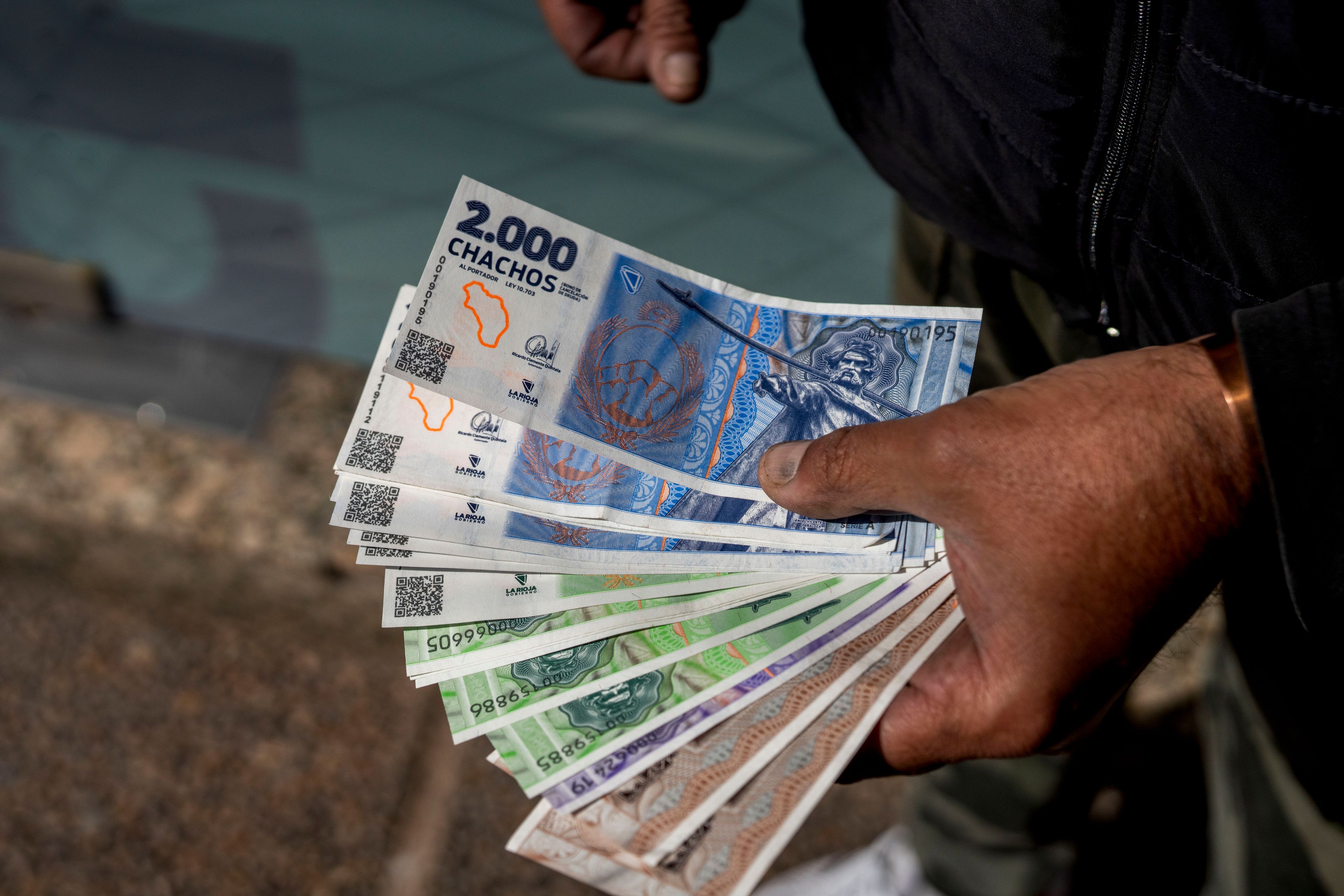 A vendor holds "chacho" currency at the Exchange Service Center to convert them to Argentine pesos in La Rioja, Argentina, Friday, Sept. 13, 2024. La Rioja province is printing this new emergency tender to pay state workers and spur the economy after the government slashed federal budgets to provinces. (AP Photo/Natalia Diaz)