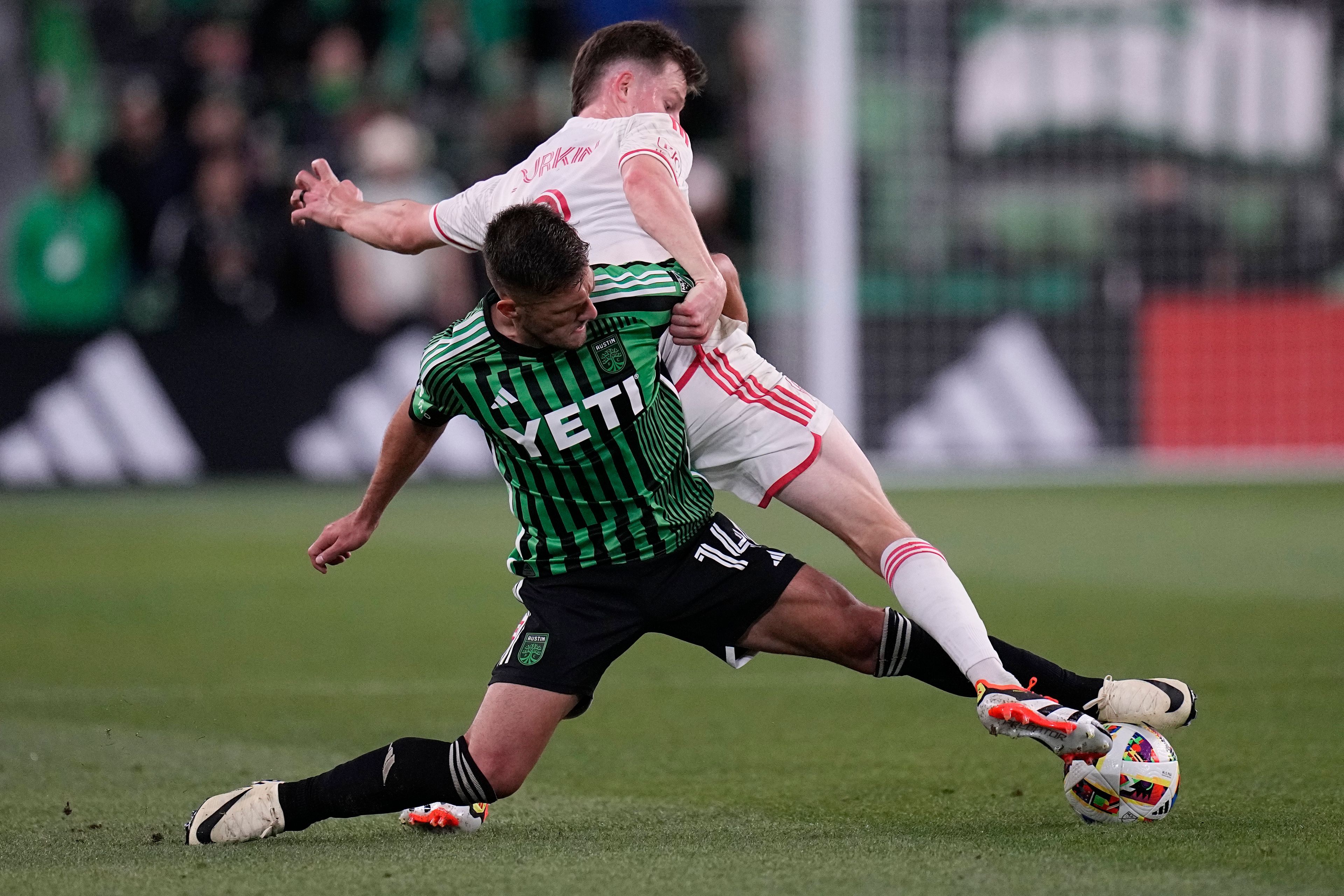 Austin FC forward Diego Rubio (14) and St. Louis City midfielder Chris Durkin, top, stretch for a pass during the second half of an MLS soccer match in Austin, Texas, Saturday, March 9, 2024. (AP Photo/Eric Gay)