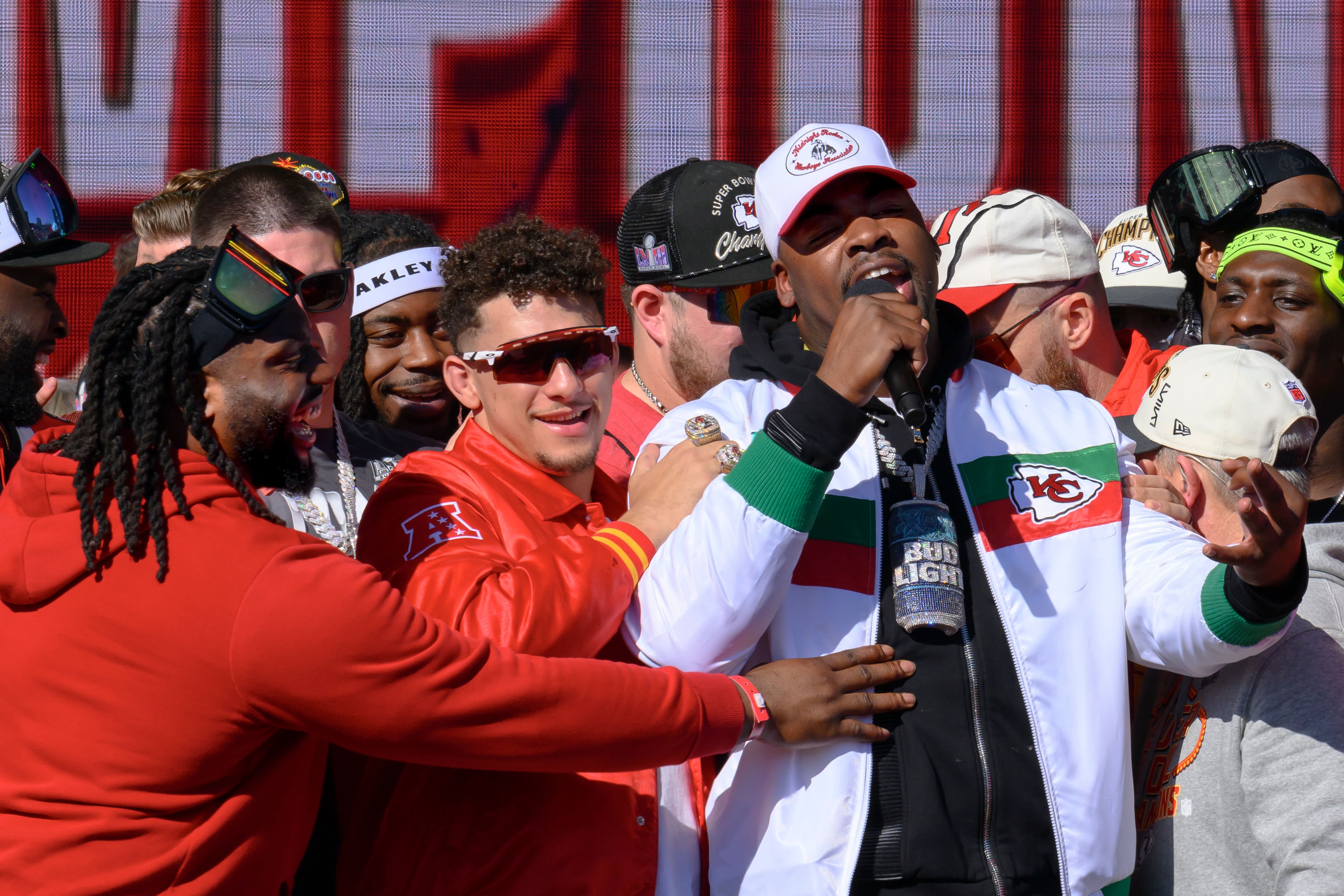 Kansas City Chiefs defensive tackle Chris Jones, right, is hugged by quarterback Patrick Mahomes, center, and defensive tackle Derrick Nnadi, at left, as he announces that he plans to play for the Chiefs next season, during their victory rally in Kansas City, Mo., Wednesday, Feb. 14, 2024. The Chiefs defeated the San Francisco 49ers Sunday in the NFL Super Bowl 58 football game. (AP Photo/Reed Hoffmann)