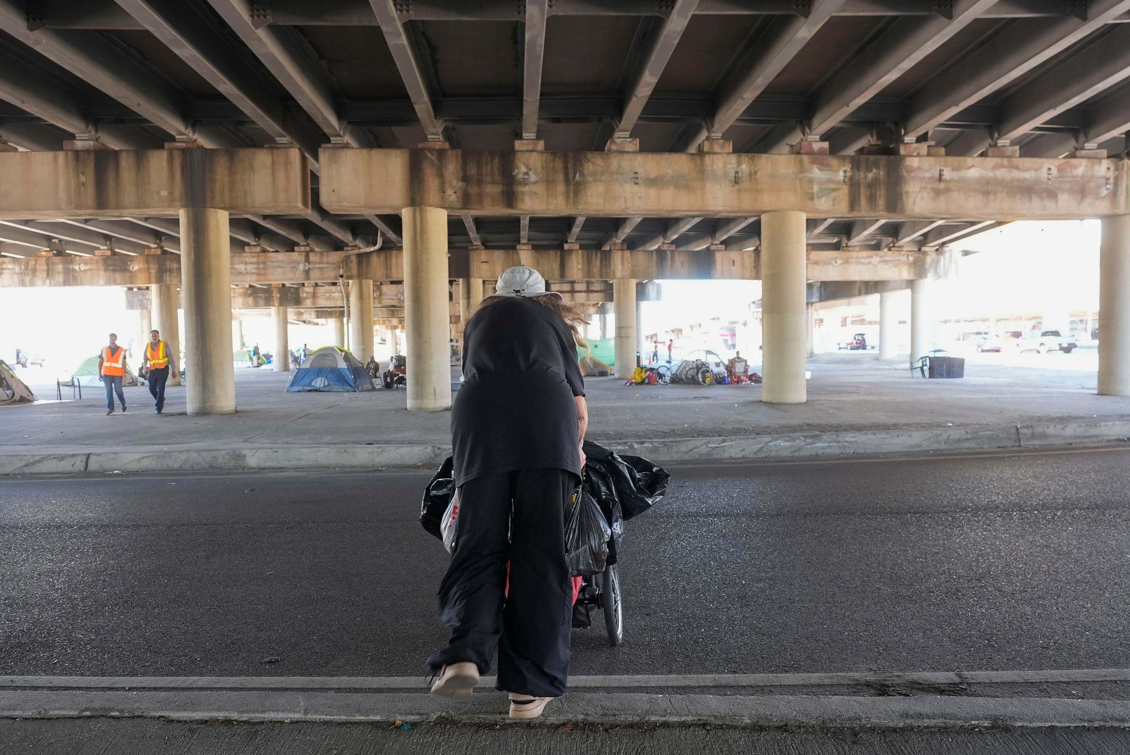 People living in a homeless encampment pick up belongings after Louisiana State police gave instructions for them to move to a different pre-designated location as they perform a sweep in advance of a Taylor Swift concert in New Orleans, Wednesday, Oct. 23, 2024. (AP Photo/Gerald Herbert)