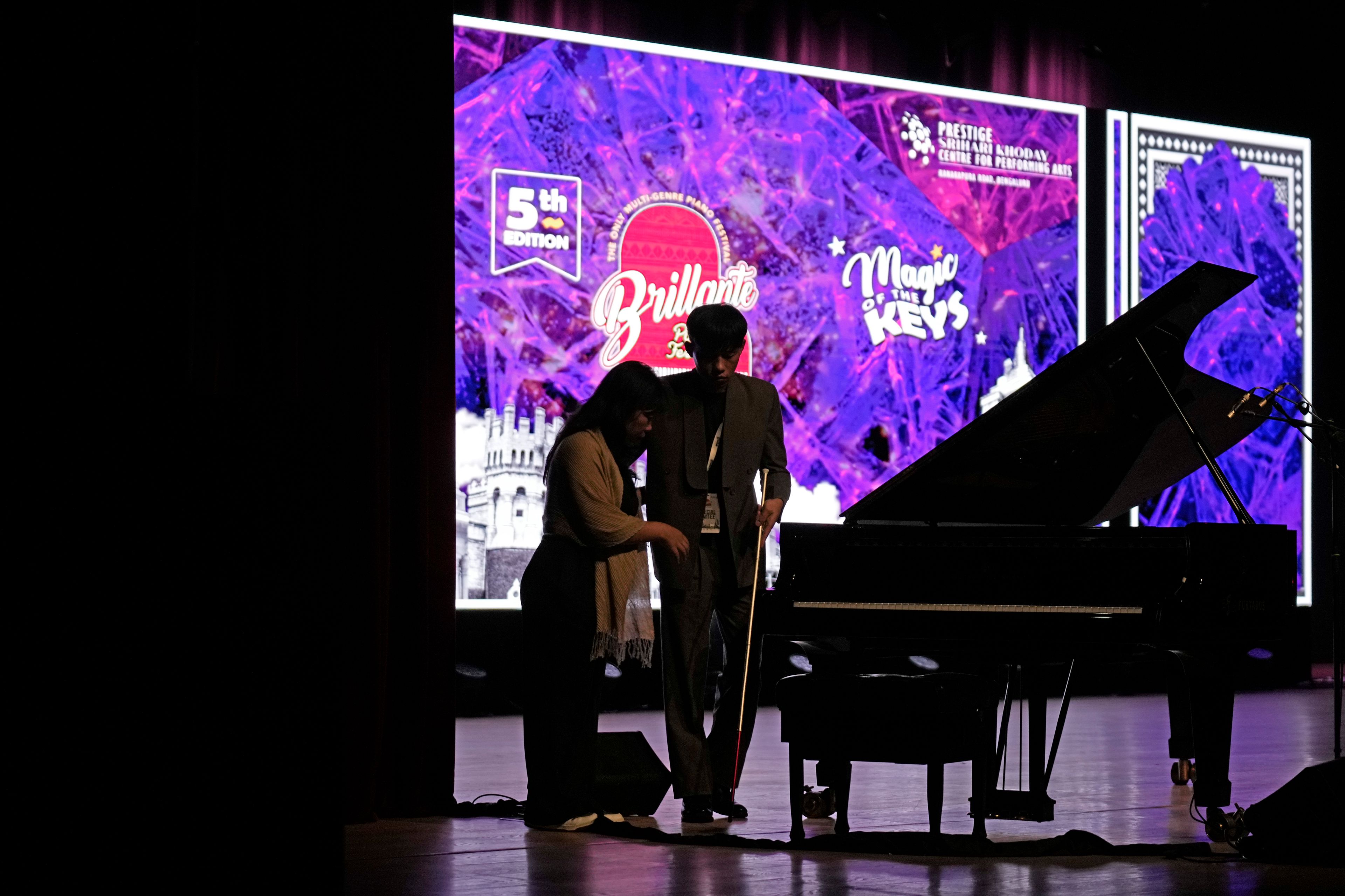 Imlibenla Jamir, 30, left, guides her brother Takosangba Pongen, 27, a blind pianist, to the stage for his performance at the two-day Brillante Piano Festival in Bengaluru, India, Sunday, Sept. 29, 2024. (AP Photo/Aijaz Rahi)