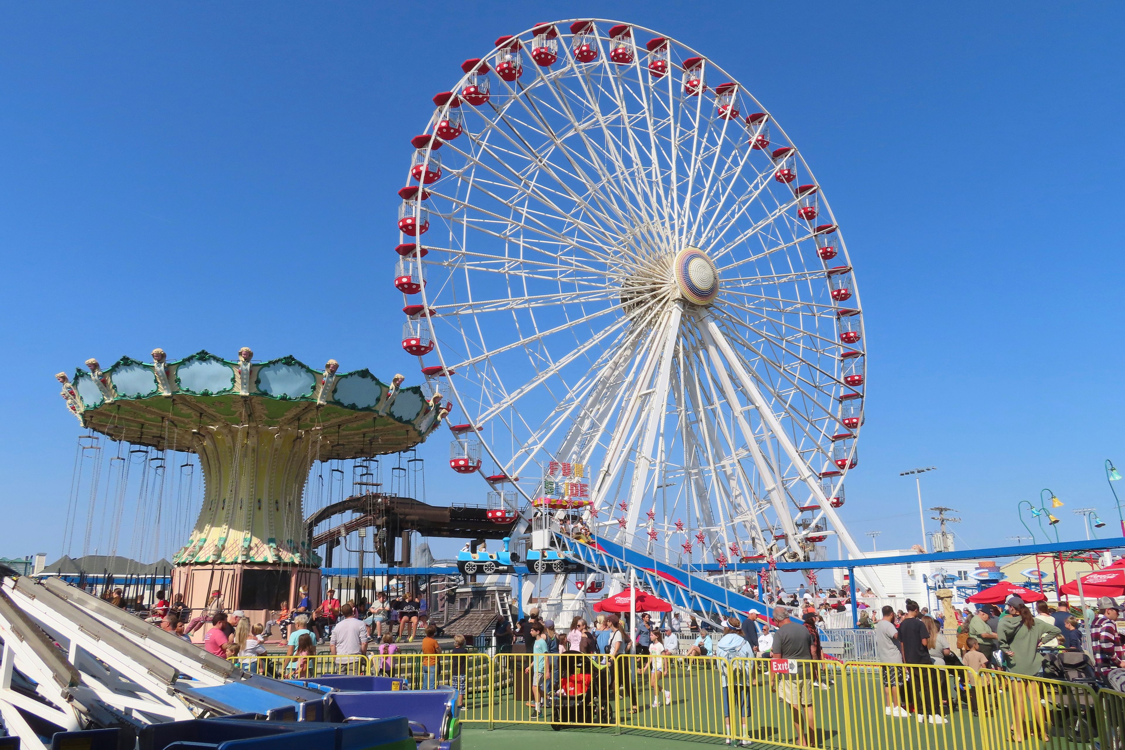 People ride the Giant Wheel and flying chair ride at Gillian's Wonderland, the popular amusement park on the boardwalk in Ocean City, N.J., during its final day of operation before shutting down for good, Sunday, Oct. 13, 2024. (AP Photo/Wayne Parry)