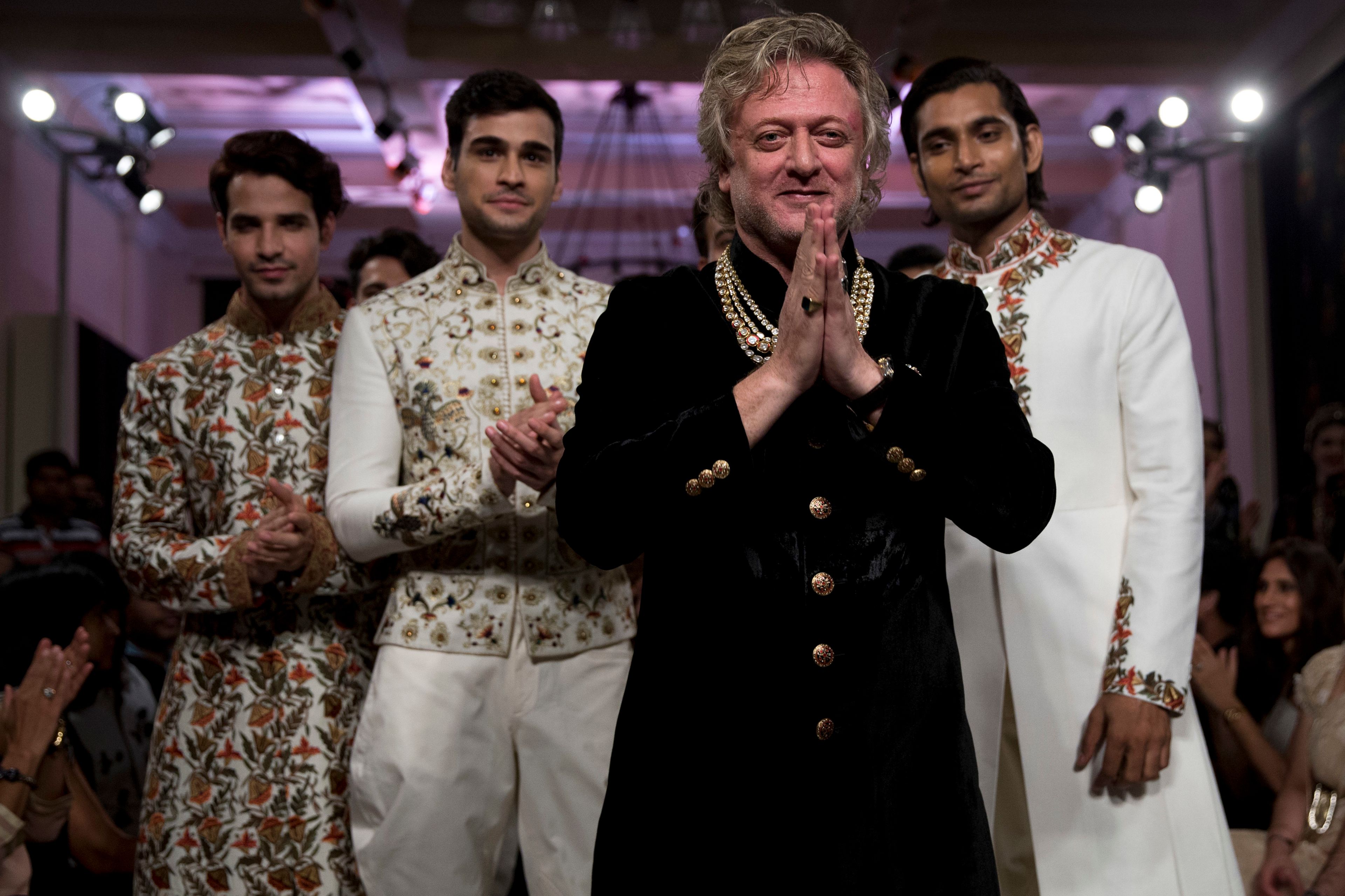 FILE - Fashion designer Rohit Bal, foreground, acknowledges the applause next to models wearing his creations at the end of his show at the Couture Week 2016 in New Delhi, India, Sunday, July 24, 2016. (AP Photo/Tsering Topgyal, File)