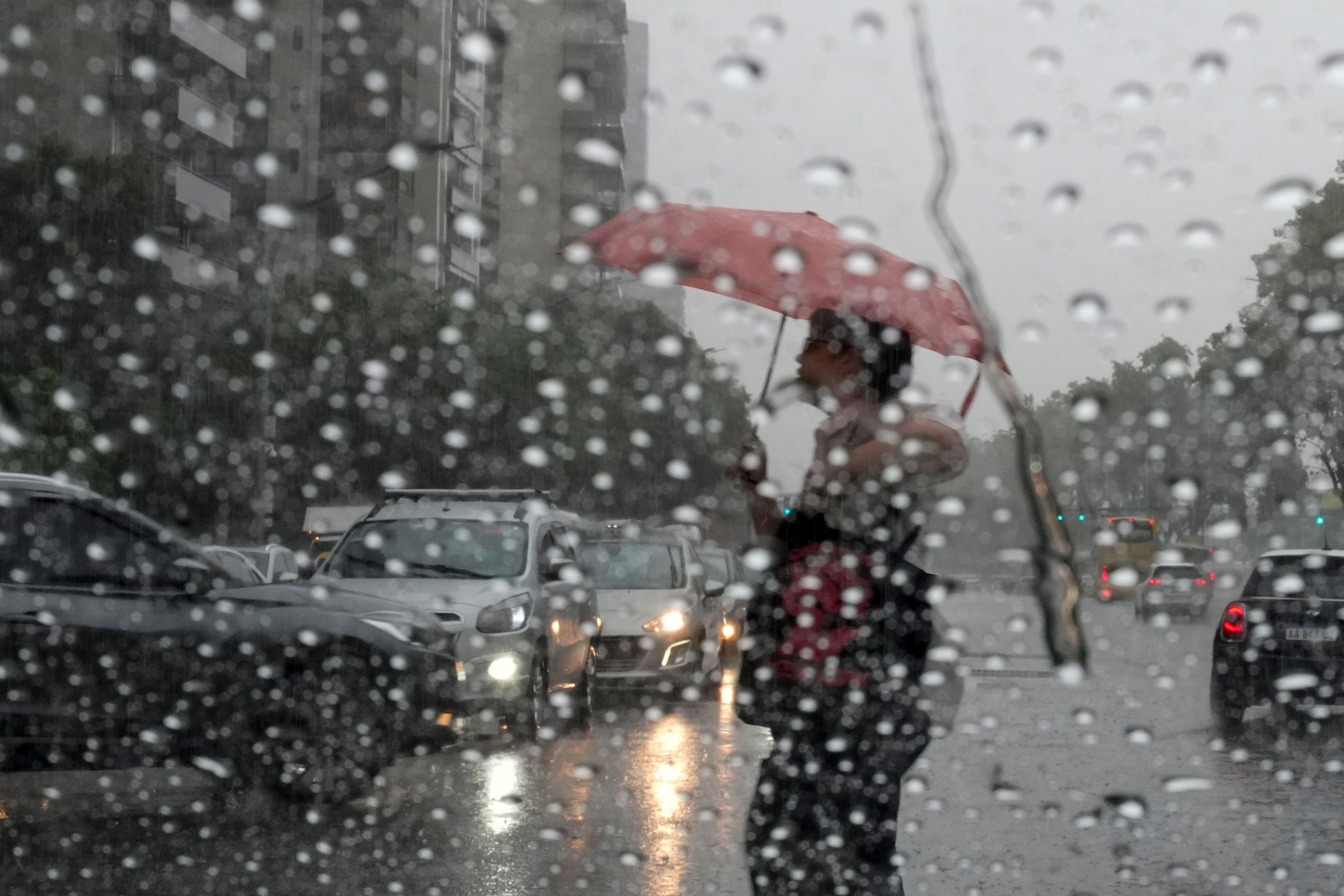 FILE - A pedestrian holding an umbrella crosses the street during a rain shower in Buenos Aires, Argentina, March 20, 2024. (AP Photo/Natacha Pisarenko, File)