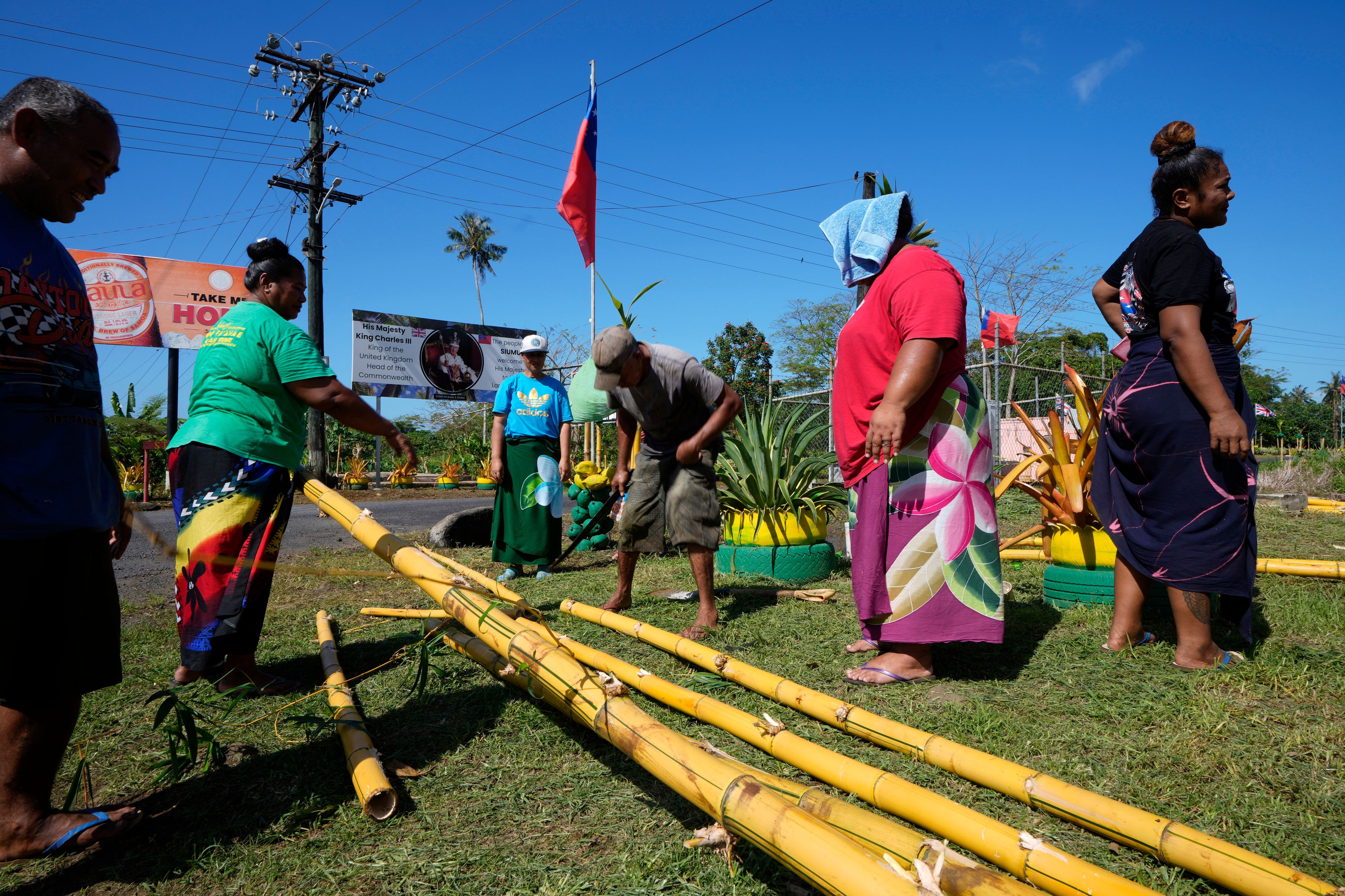 People from the village of Siumu, Samoa, work on decorating the entrance of their village on Monday, Oct. 21, 2024, as they prepare for the arrival of King Charles III. (AP Photo/Rick Rycroft)