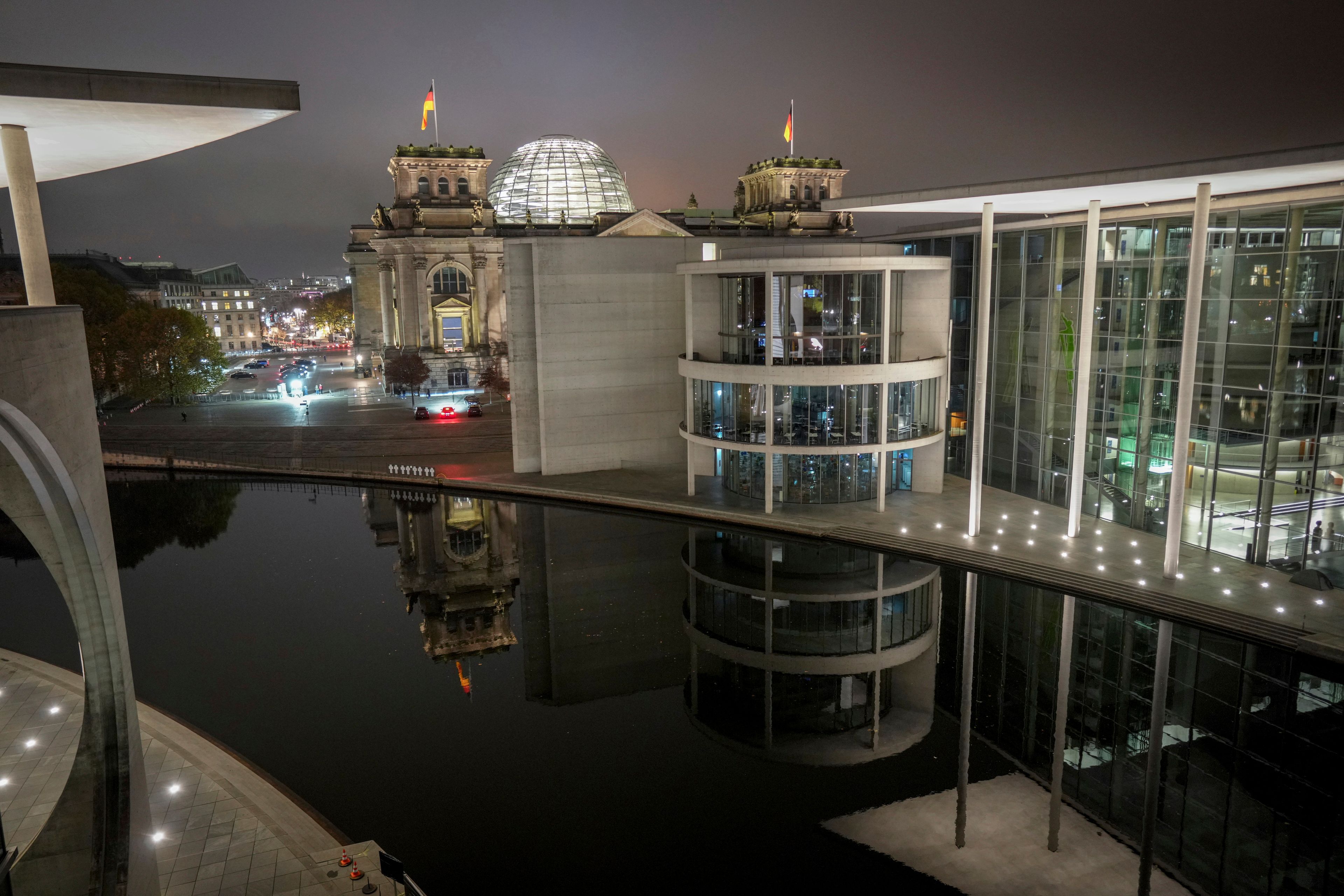 Parts of the Reichstag building with the Bundestag and the Paul Löbe House in Berlin's government district are reflected in the Spree at night, early Thursday, Nov. 7, 2024. (Kay Nietfeld/dpa via AP)