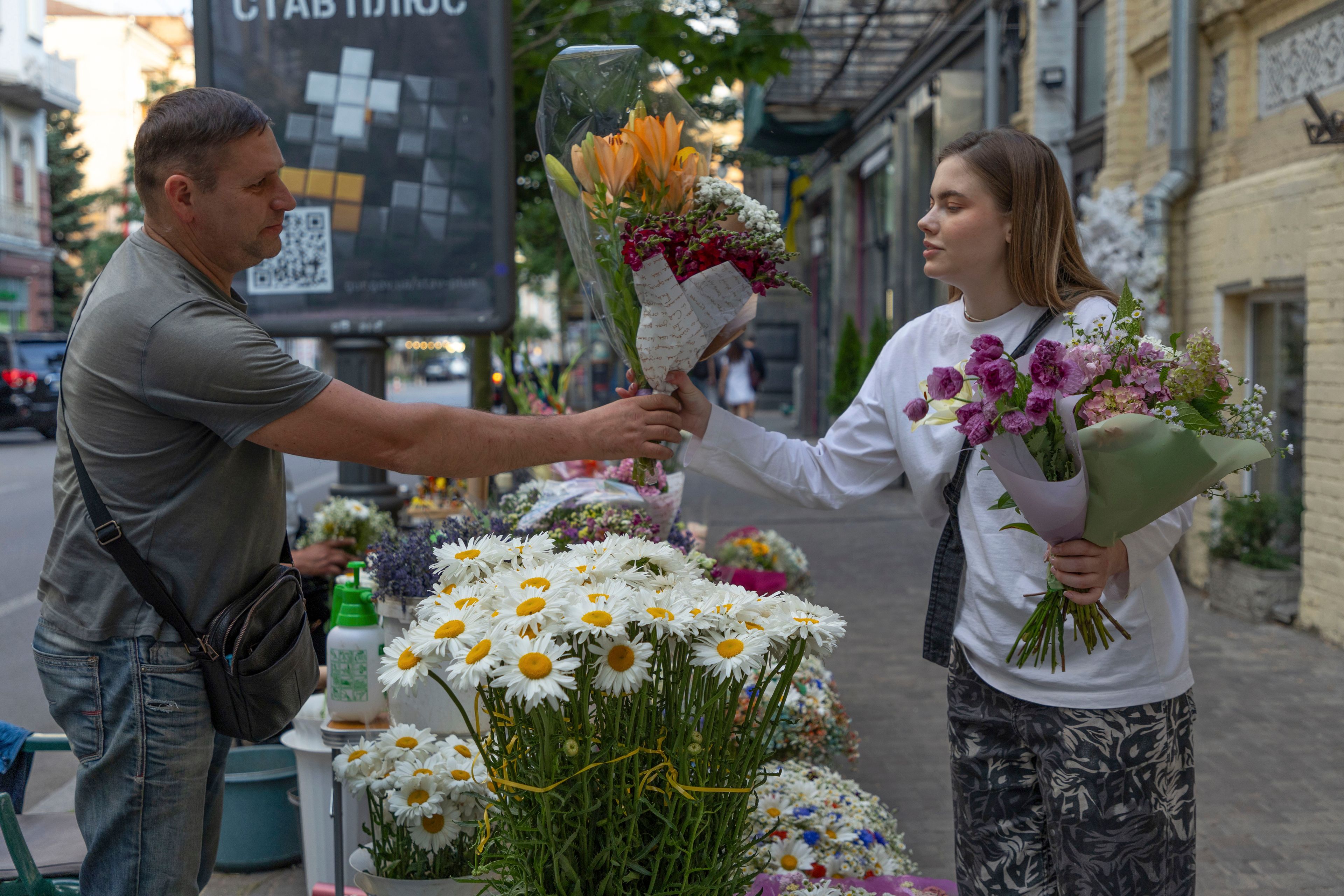 A woman buys bouquets of flowers at a street flower stall in Kyiv, Ukraine, Tuesday, June 25, 2024. Despite hardships brought by war flowers fill Kyiv and other Ukrainian cities. They burst out of planters that line the capital's backroads and grand boulevards and are fixed to lampposts. (AP Photo/Anton Shtuka)