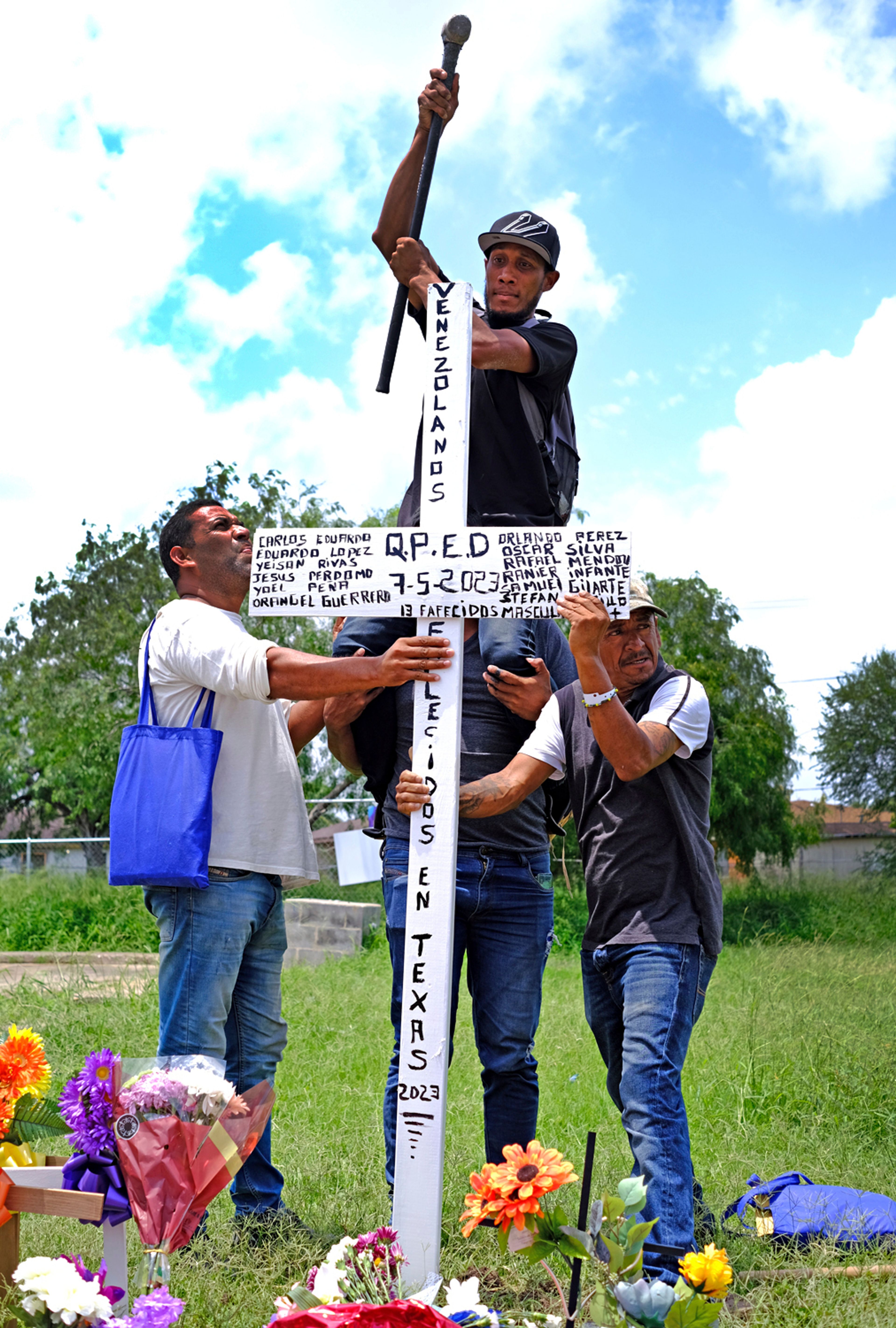 Four people place a wooden cross in the ground, Tuesday, May 9, 2023, in Brownsville, Texas, that they built and hand-painted in homage to the eight Venezuelans who lost their lives when the driver of an SUV killed eight people when it slammed into a bus stop. A Texas jury has found George Alvarez guilty of intoxication manslaughter, Friday, June 28, 2024 over the deaths of eight people who were struck by an SUV that plowed into a crowded bus stop outside a migrant shelter on the U.S.-Mexico border. (Miguel Roberts/The Brownsville Herald via AP, File)