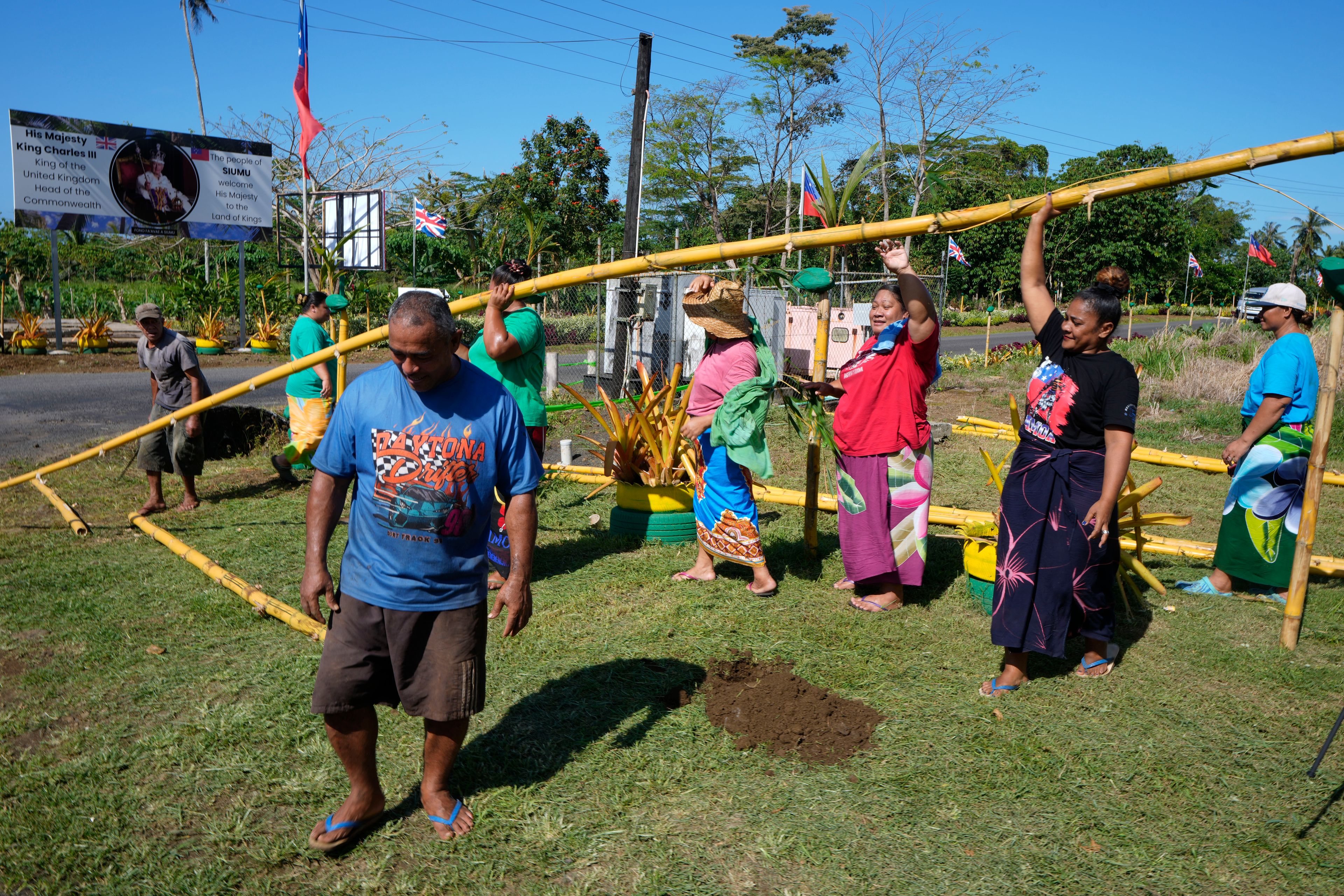 People from the village of Siumu, Samoa, work on decorating the entrance of their village on Monday, Oct. 21, 2024, as they prepare for the arrival of King Charles III. (AP Photo/Rick Rycroft)