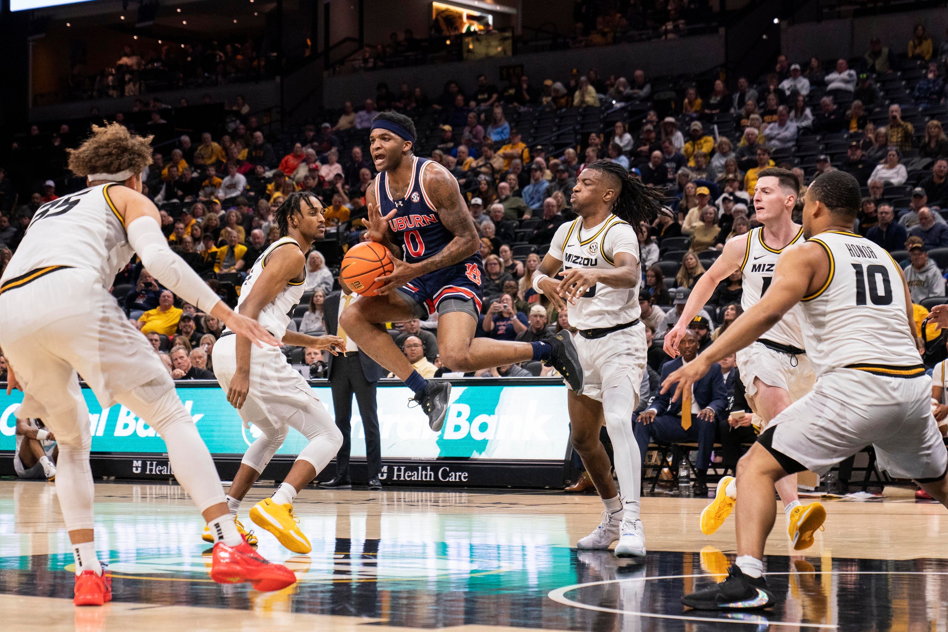 Auburn's K.D. Johnson, center, leaps as he passes while surrounded by Missouri players during the first half of an NCAA college basketball game Tuesday, March 5, 2024, in Columbia, Mo. (AP Photo/L.G. Patterson)