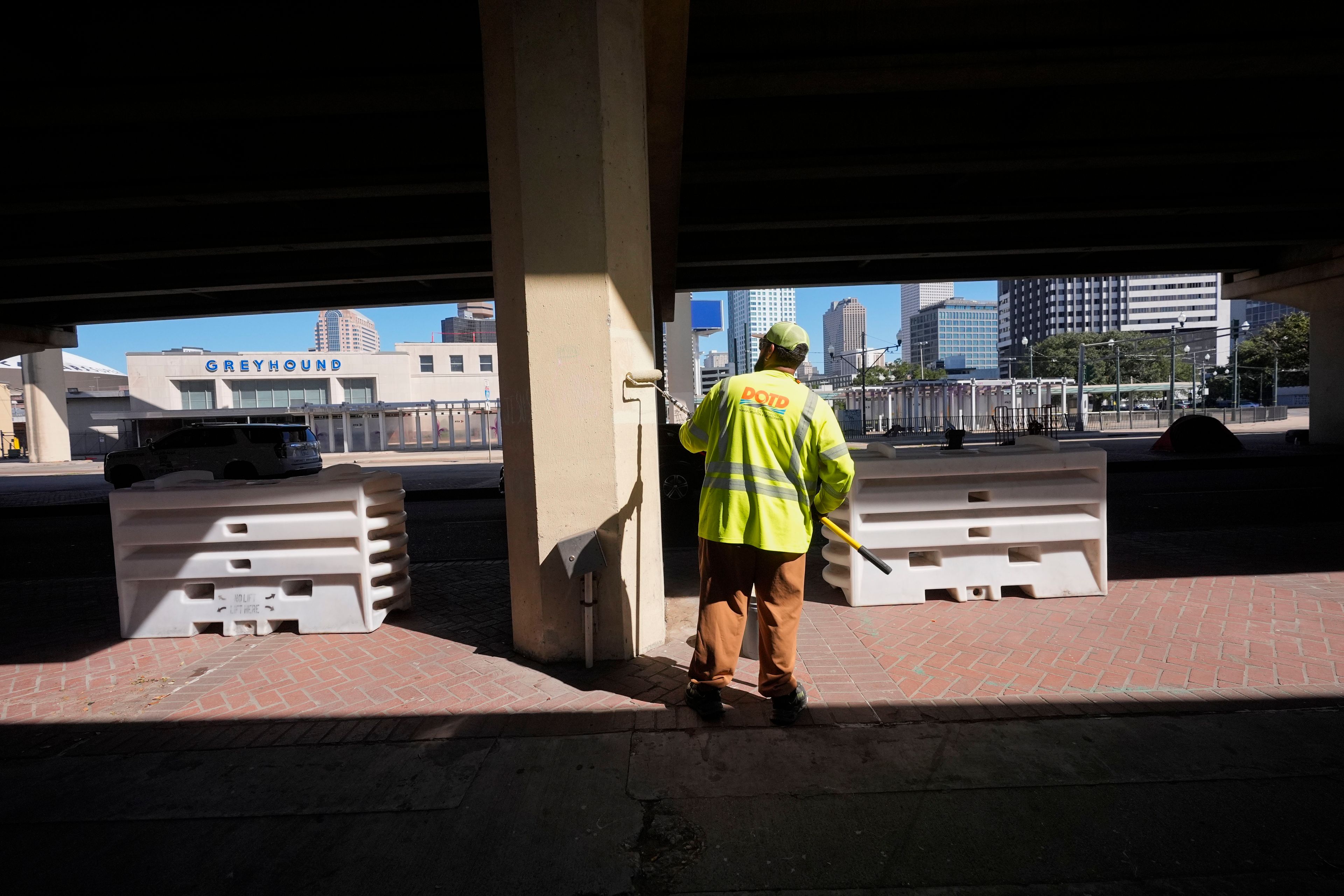 A Louisiana Department of Transportation and Development employee paints a support under an elevated expressway that was cleared out after Louisiana State police gave instructions to people living in a homeless encampment there to move to a different pre-designated location as they perform a sweep in advance of a Taylor Swift concert in New Orleans, Wednesday, Oct. 23, 2024. (AP Photo/Gerald Herbert)