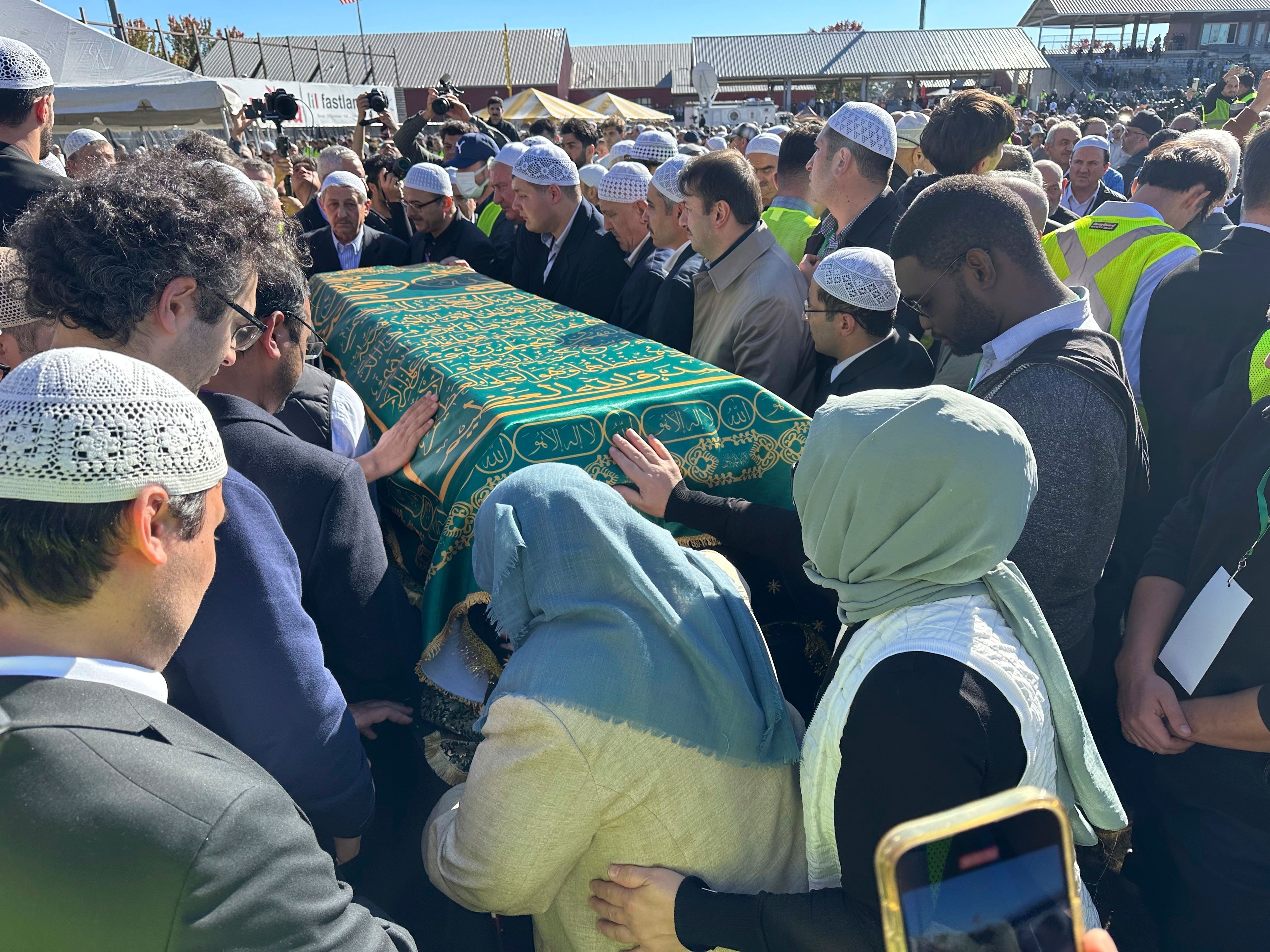 Fethullah Gulen's sister, Fazilet Korucuk, in blue head covering, touches his casket at a prayer service in Augusta, on Thursday, Oct. 24, in Augusta, New Jersey.(AP Photo/Mike Rubinkam)