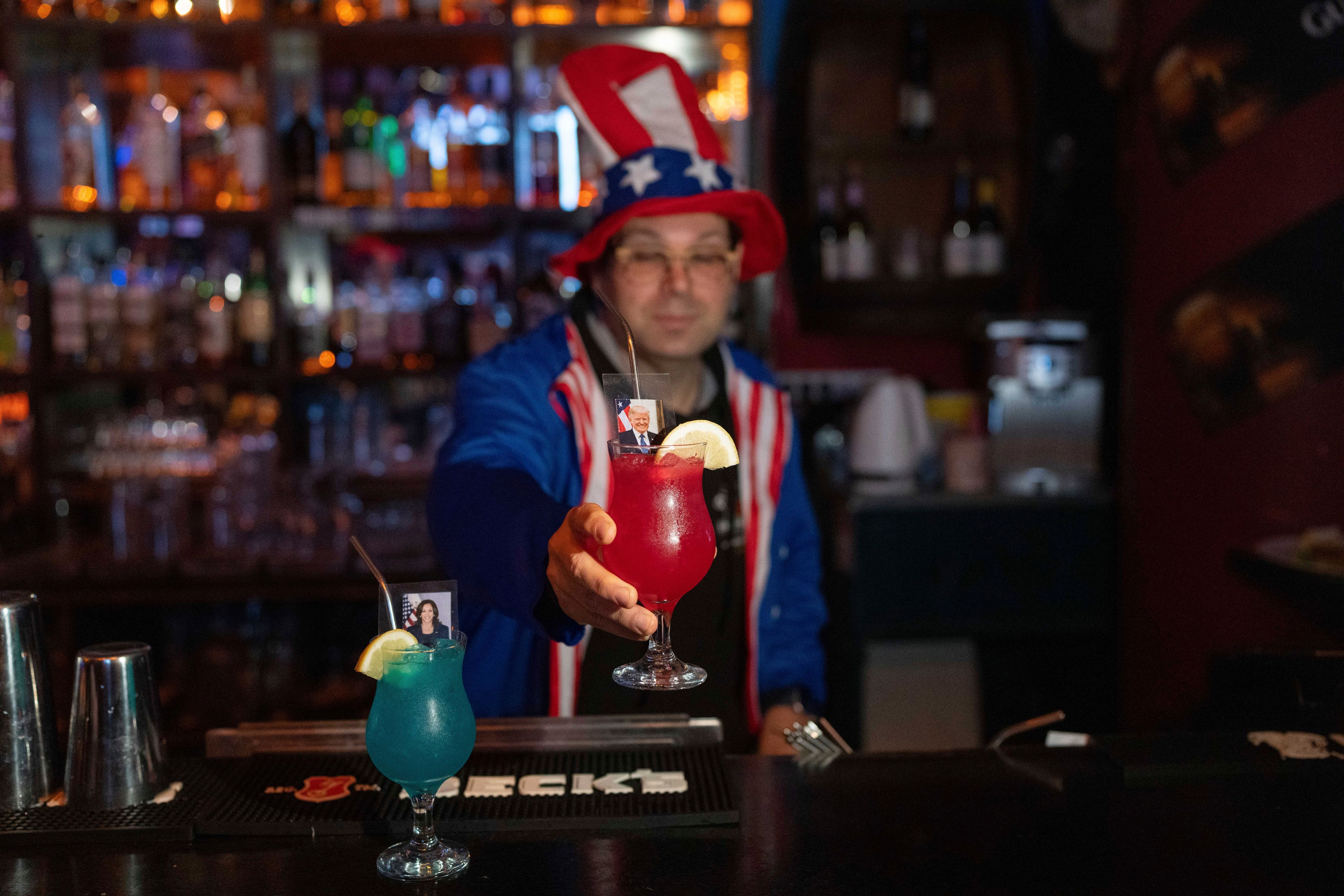 Bartender serves drinks with the pictures of the Republican presidential nominee former President Donald Trump and Democratic presidential nominee Vice President Kamala Harris on U.S. Election Day to customers watching results roll in at a bar in Jerusalem, Wednesday, Nov. 6, 2024. (AP Photo/Ohad Zwigenberg)