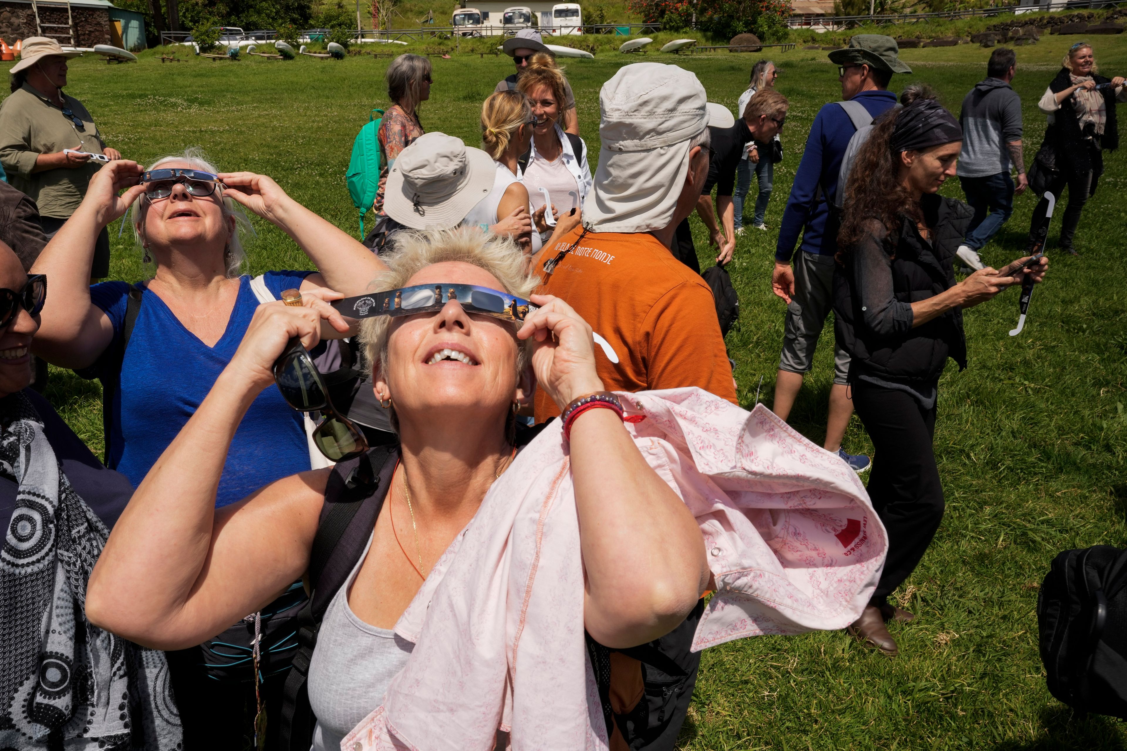 Tourists test out special glasses for the following day's annular solar eclipse on Easter Island, Chile, Tuesday, Oct. 1, 2024. (AP Photo/Esteban Felix)