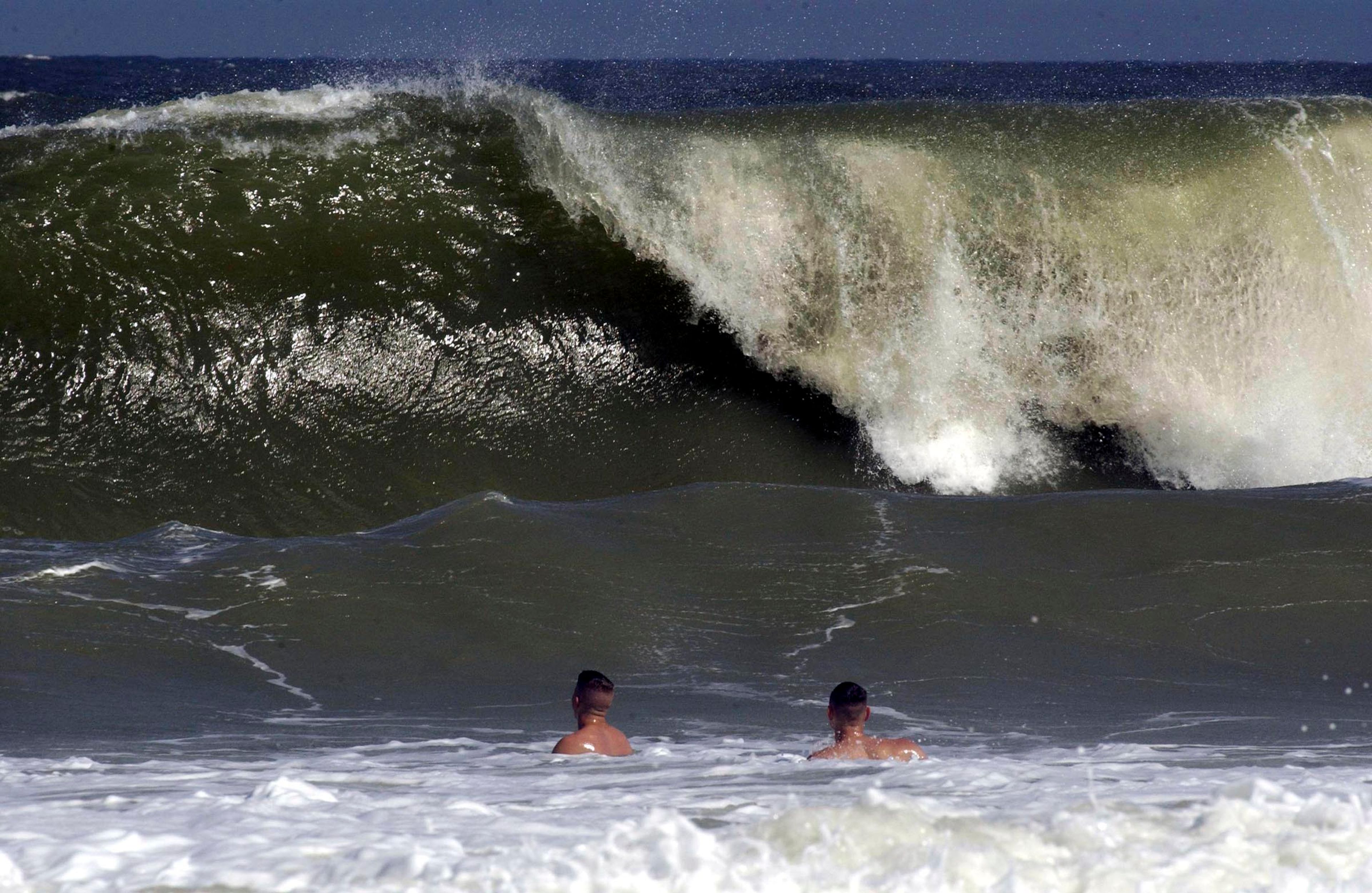FILE - Shaun Clark, left, and Jim Donnelly watch as a big wave starts to come ashore at Fernandina Beach, in Nassau County, Fla., Sept. 16, 2003. A man on Florida’s east coast was bitten by a shark this weekend, but is now recovering, Nassau County authorities said Sunday, June 30, 2024, in the third shark attack in state waters over the past month. (Bob Mack/The Florida Times-Union via AP)