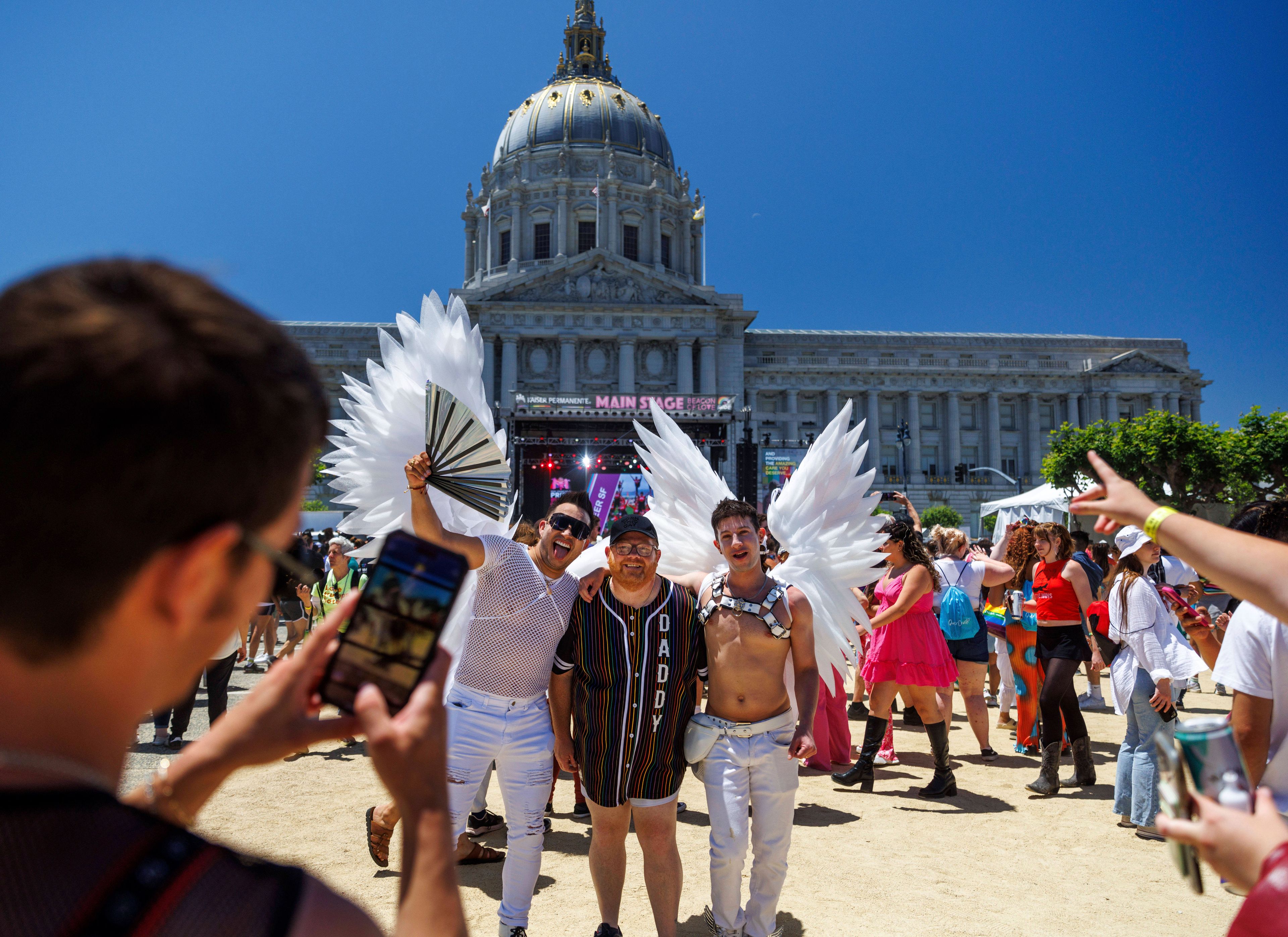 Revelers pose for photos with participants dressed in wings in front of San Francisco City Hall during a Pride Parade, Sunday, June 30, 2024, in San Francisco. (AP Photo/Ethan Swope)