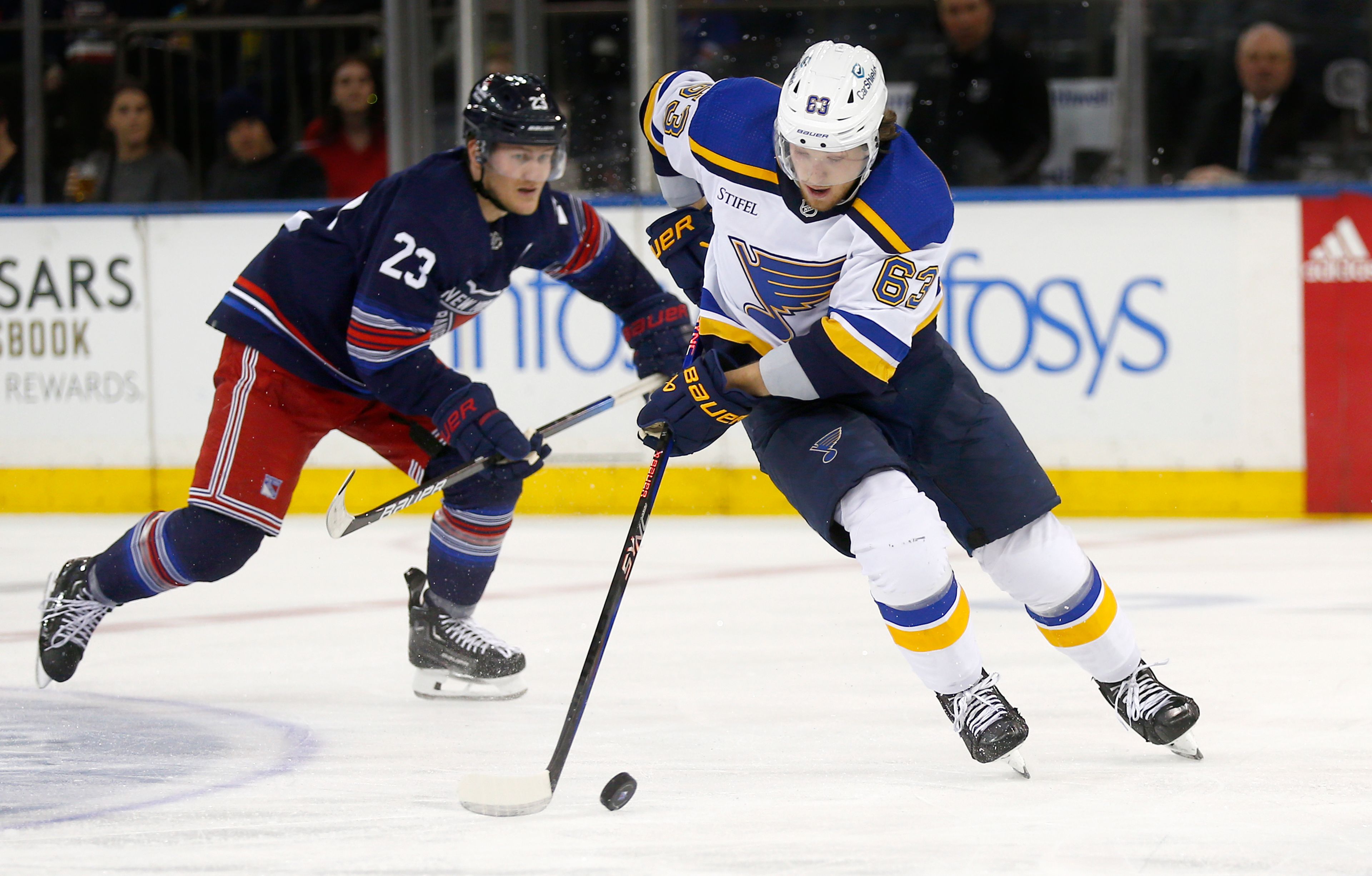 St. Louis Blues forward Jake Neighbours (63) carries the puck while New York Rangers defenseman Adam Fox (23) follows during the second period of an NHL hockey game Saturday, March 9, 2024, in New York. (AP Photo/John Munson)